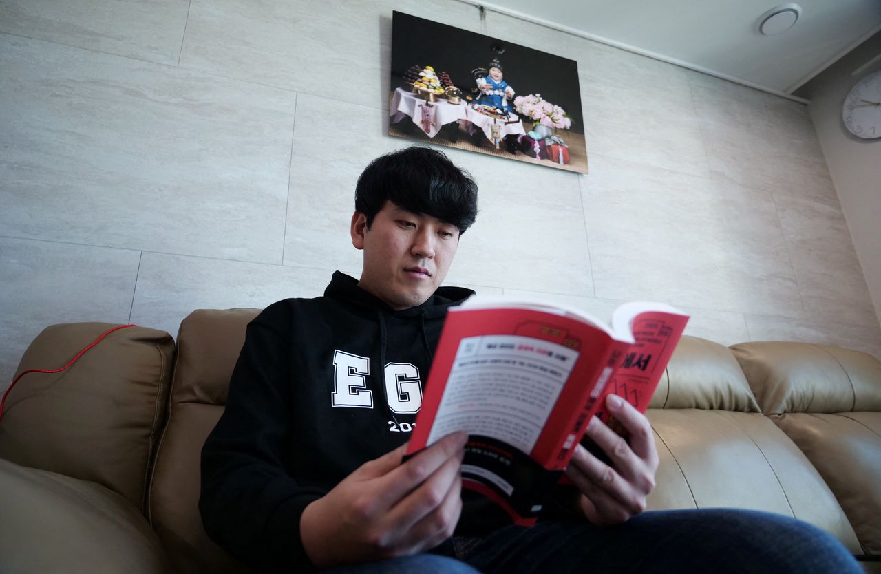 Jang Sung-won, 32, who owns YouTube channel Saver King, reads a book at his home in Paju, South Korea, February 23, 2022. Picture taken February 23, 2022.   REUTERS/Daewoung Kim