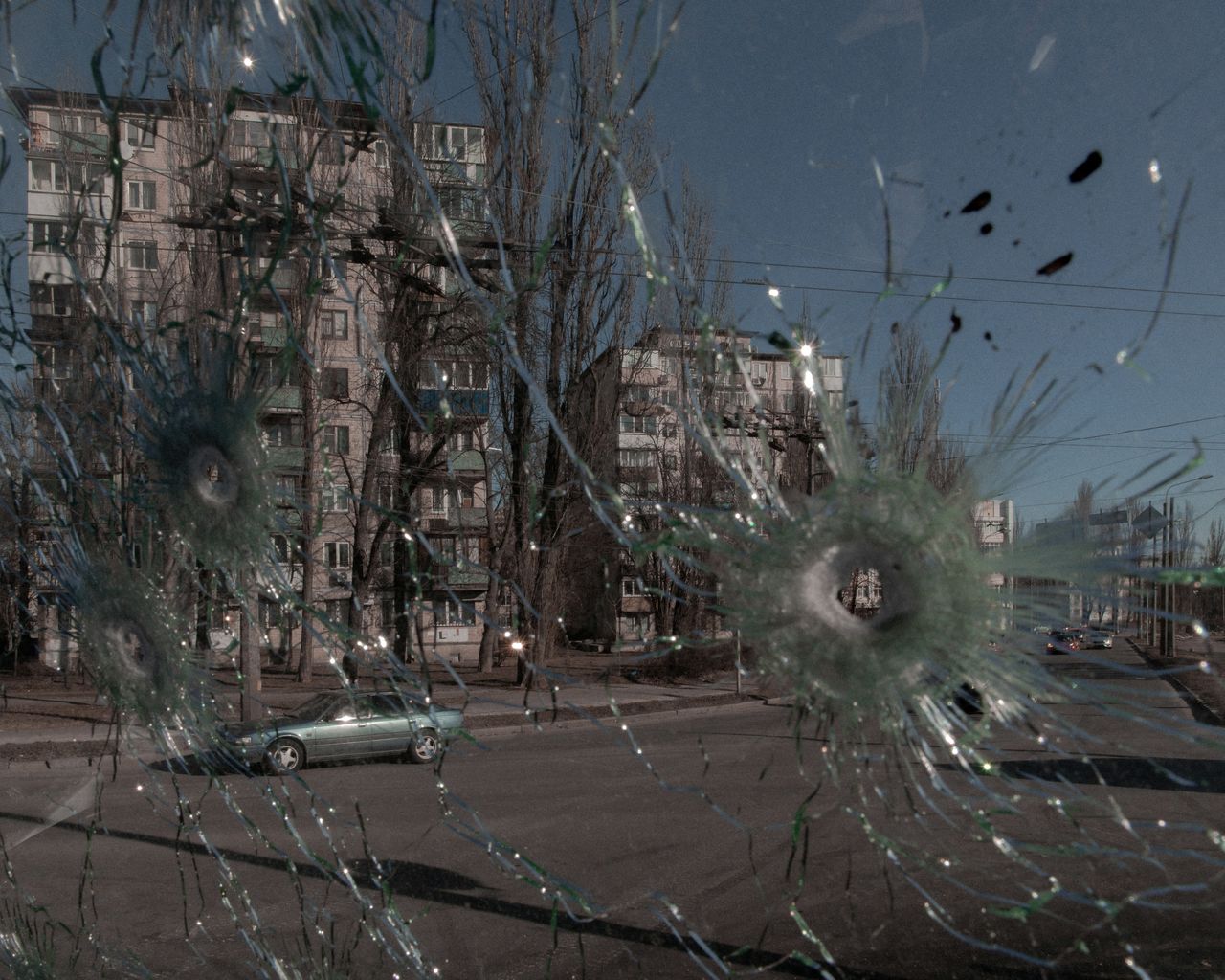 Cars are seen through the damaged window of a vehicle hit by bullets, as Russia