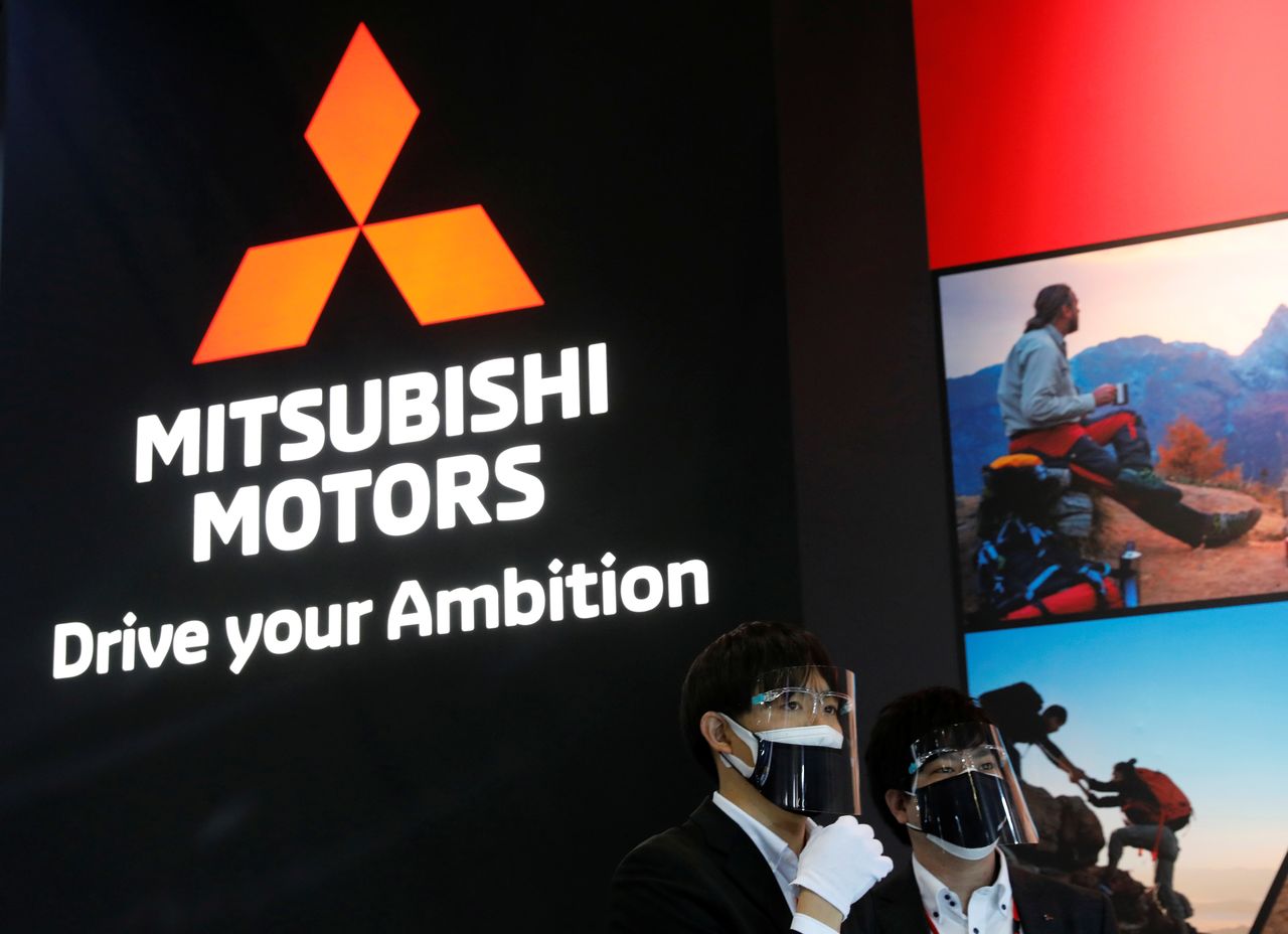 Staff members wearing protective masks and face shields, amid the coronavirus disease (COVID-19) pandemic, stand in front of the logo of Mitsubishi Motors at Tokyo Auto Salon 2022 at Makuhari Messe in Chiba, east of Tokyo, Japan January 14, 2022. REUTERS/Kim Kyung-Hoon/Files