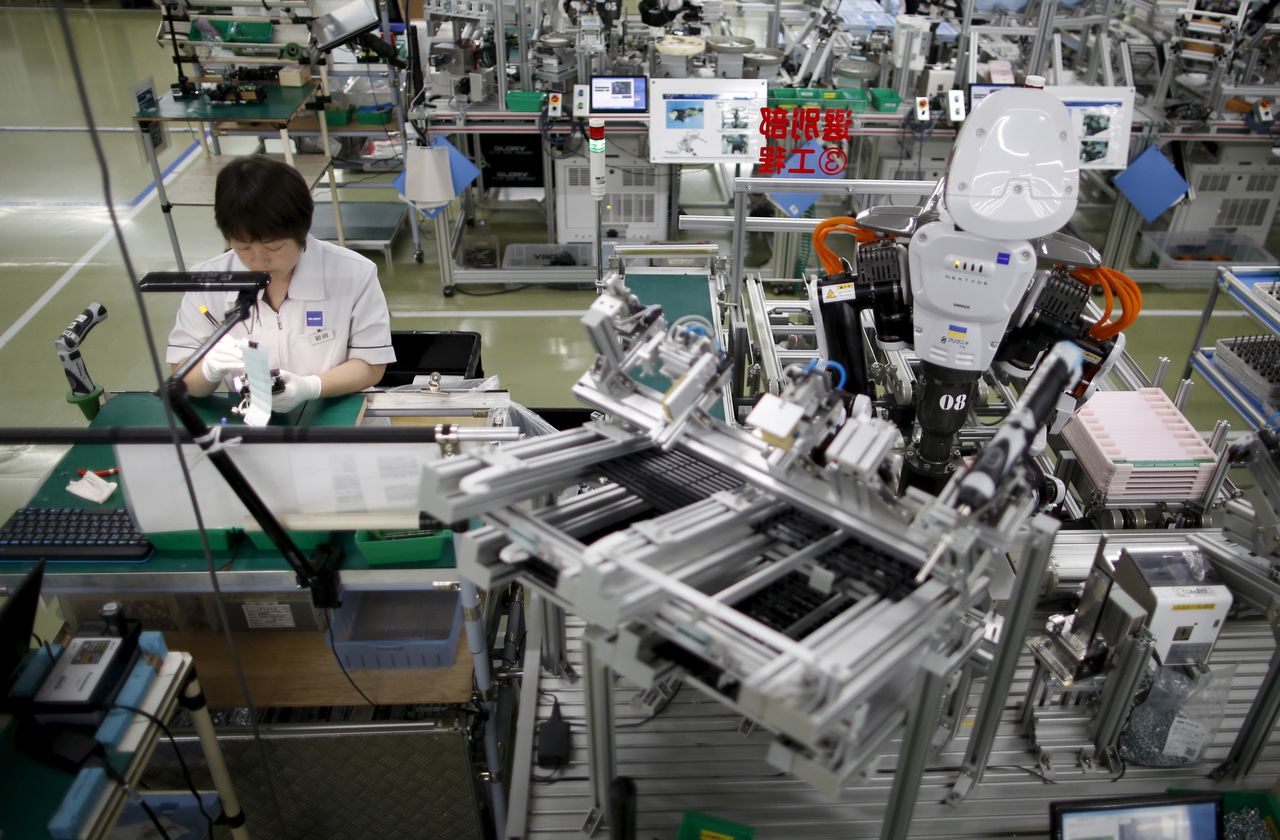 FILE PHOTO: A humanoid robot works side by side with an employee in the assembly line at a factory of Glory Ltd., a manufacturer of automatic change dispensers, in Kazo, north of Tokyo
, Japan, July 1, 2015. REUTERS/Issei Kato