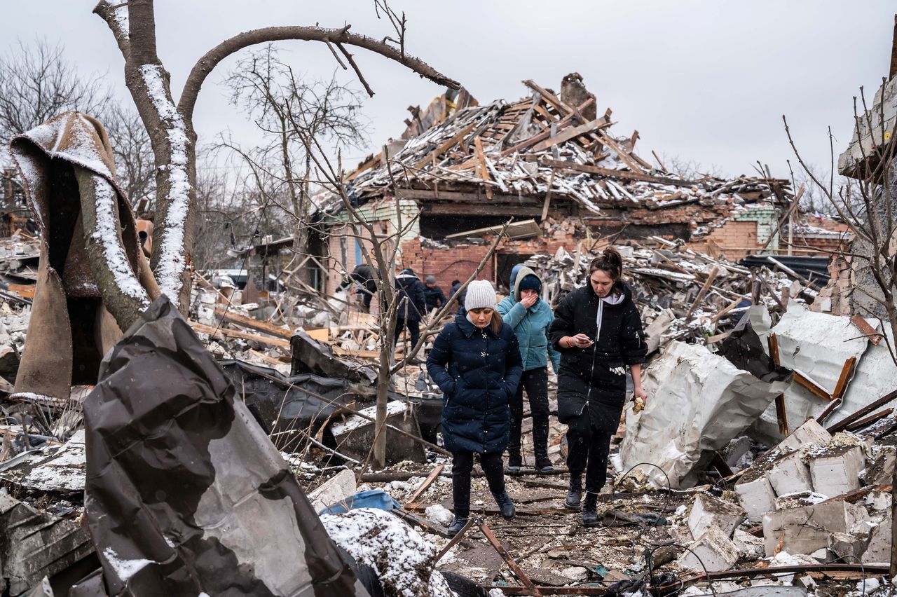 Women walk among remains of residential buildings destroyed by shelling, as Russia