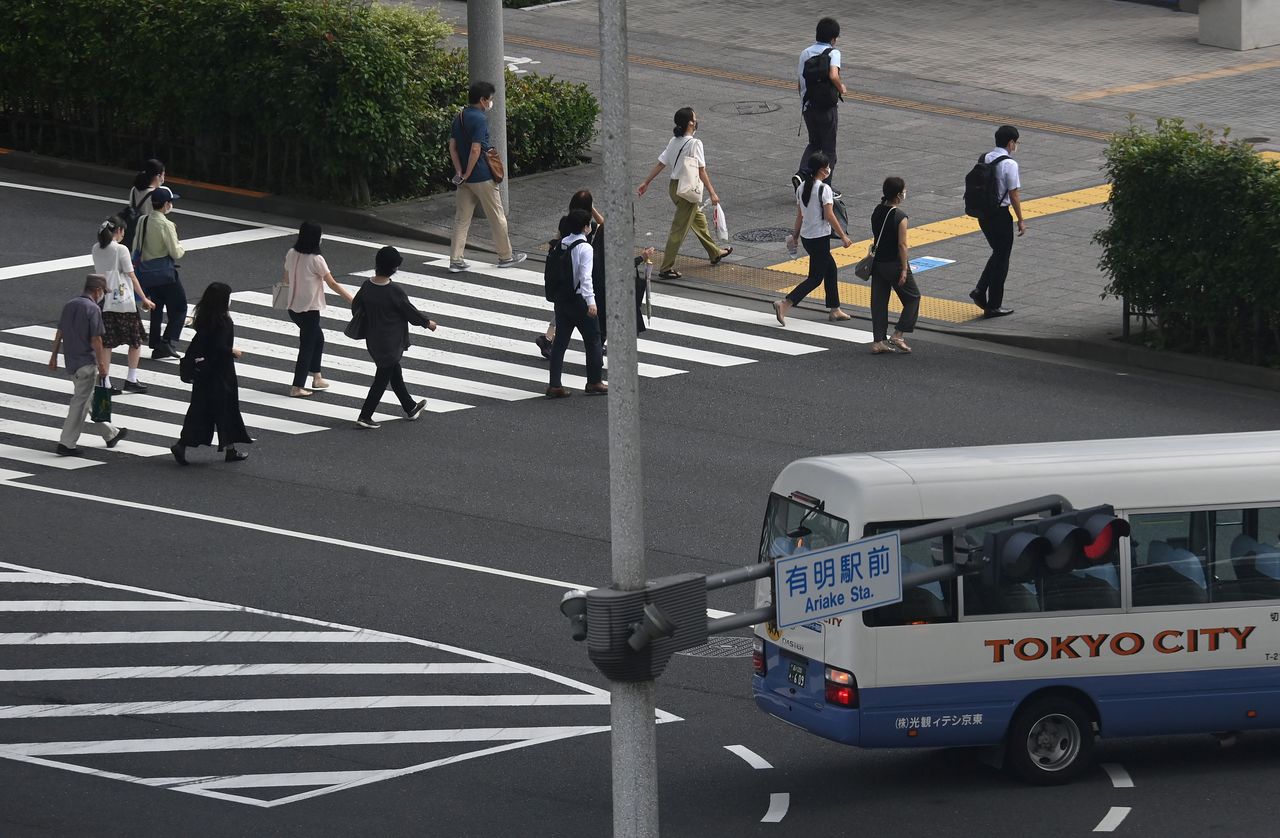 Workers cross a road during the morning rush hour, ahead of the Tokyo 2020 Olympic Games that have been postponed to 2021 due to the coronavirus disease (COVID-19) pandemic, in Tokyo, Japan, July 15, 2021. REUTERS/Toby Melville