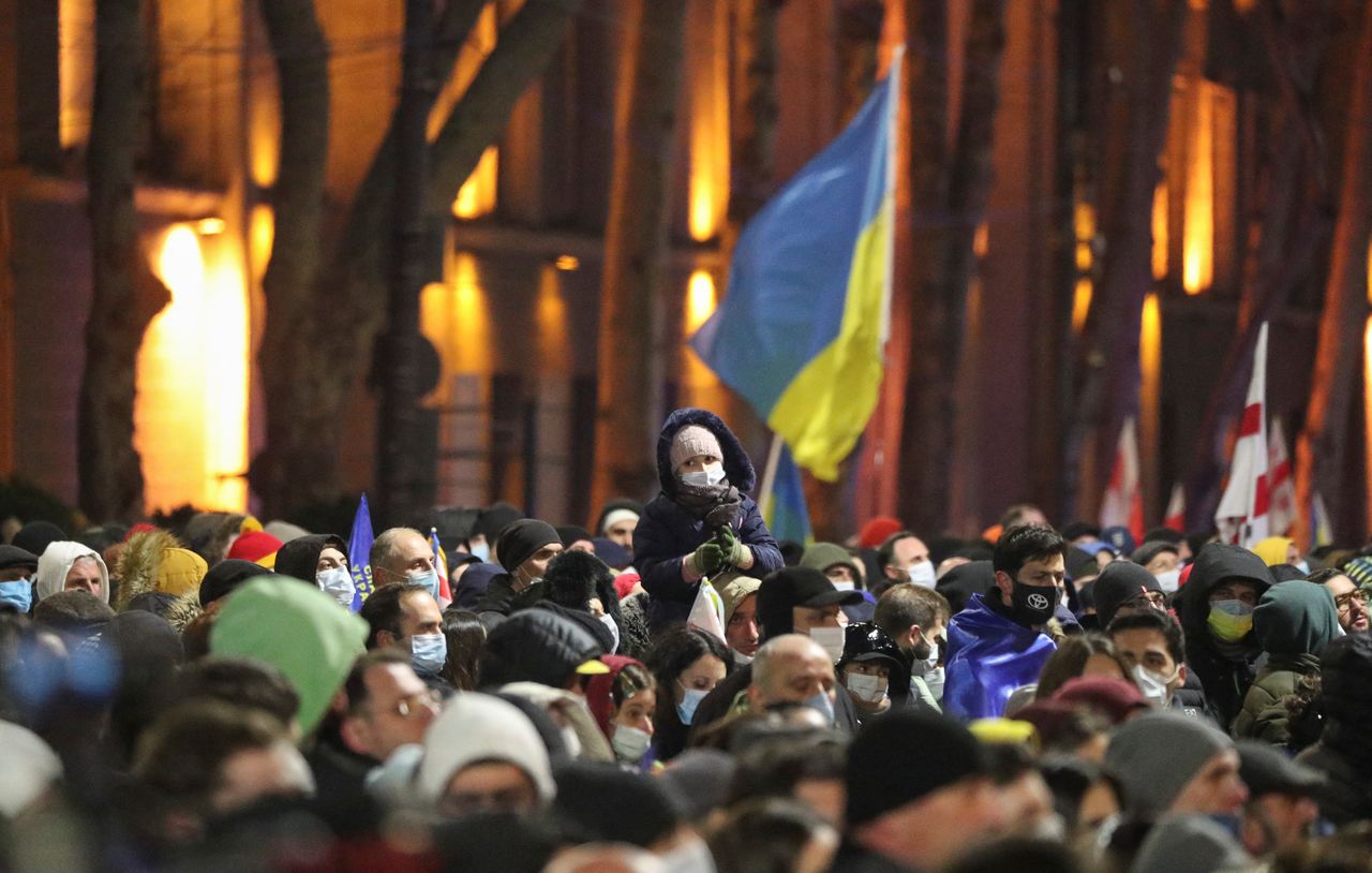 Demonstrators gather in front of a screen to watch the broadcast of the live speech of Ukraine