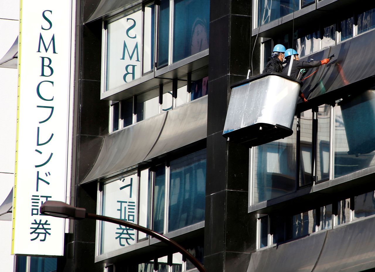 FILE PHOTO: Workers clean windows next to a signboard of Sumitomo Mitsui Financial Group