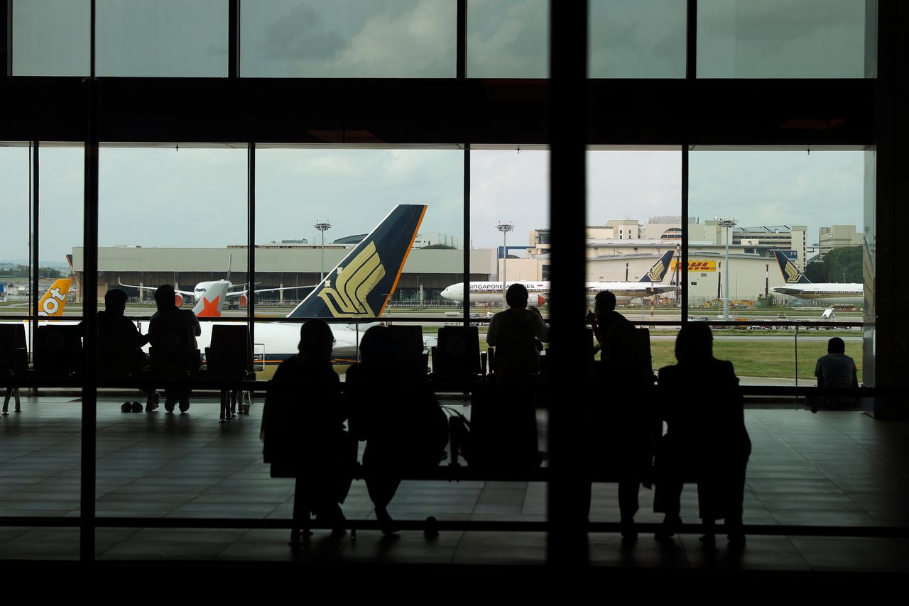 FILE PHOTO: People look at a Singapore Airlines plane, amid the spread of the coronavirus disease (COVID-19), at a viewing gallery of the Changi Airport in Singapore October 12, 2020. REUTERS/Edgar Su
