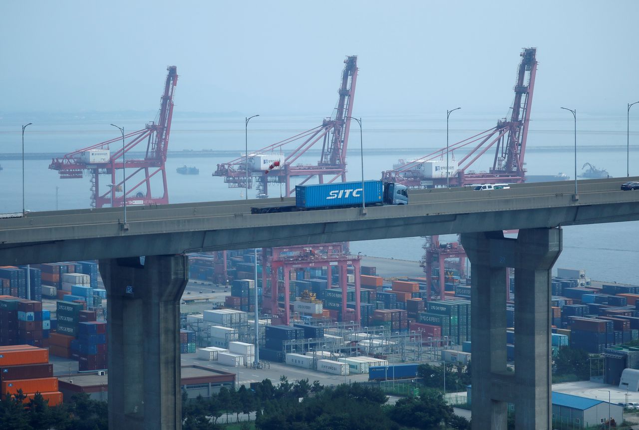 FILE PHOTO: A truck carrying a shipping container travels past cranes at Pyeongtaek port in Pyeongtaek, South Korea, July 9, 2020.    REUTERS/Kim Hong-Ji