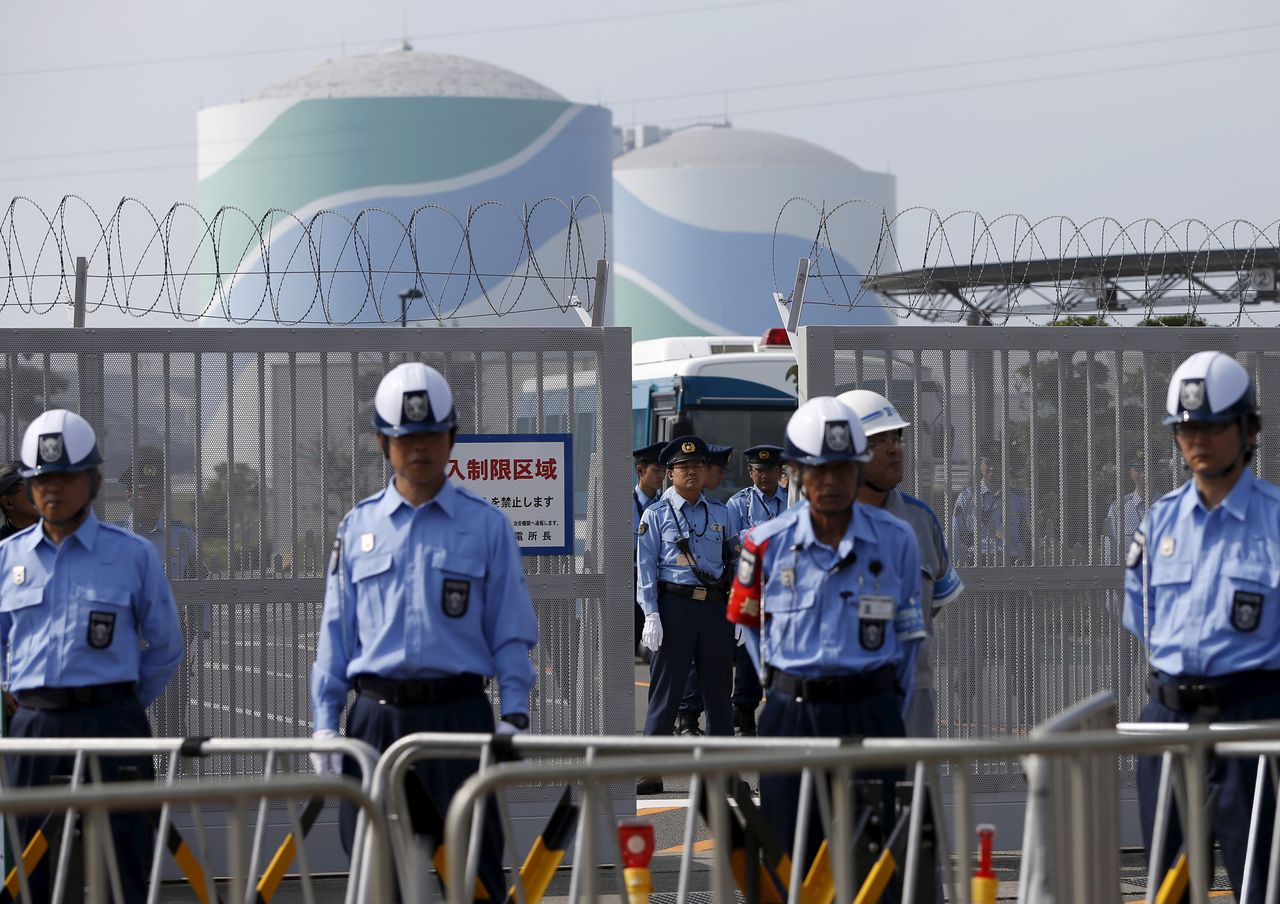 FILE PHOTO: Police officers and security personnel stand guard at an entrance of Kyushu Electric Power