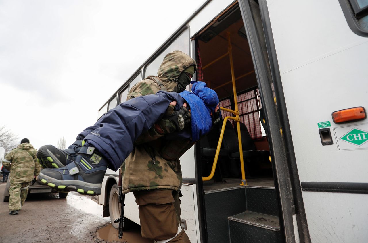 A service member of pro-Russian troops carries a child, who was evacuated from Mariupol area to a refugee camp in the settlement of Bezymennoye, into a bus before the departure for the territory of Russia during Ukraine-Russia conflict in the Donetsk region, Ukraine March 8, 2022. REUTERS/Alexander Ermochenko