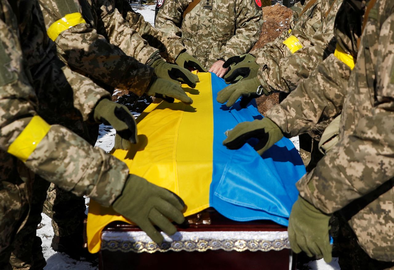 Members of the Honour Guard place the national flag to a coffin with a body of the member of the Ukrainian Armed Forces, Valerii, who was killed during Russia