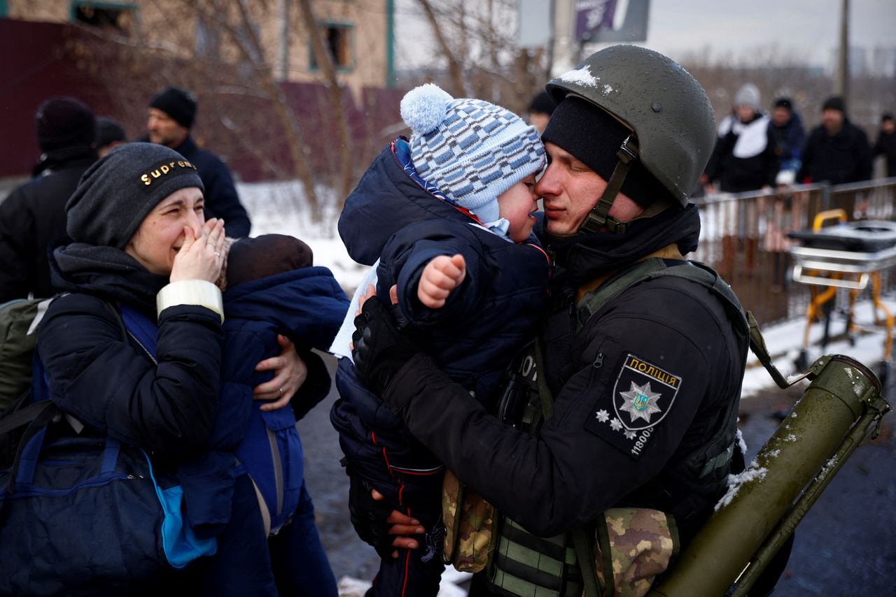 A police officer says goodbye to his son as his family flees from advancing Russian troops as Russia