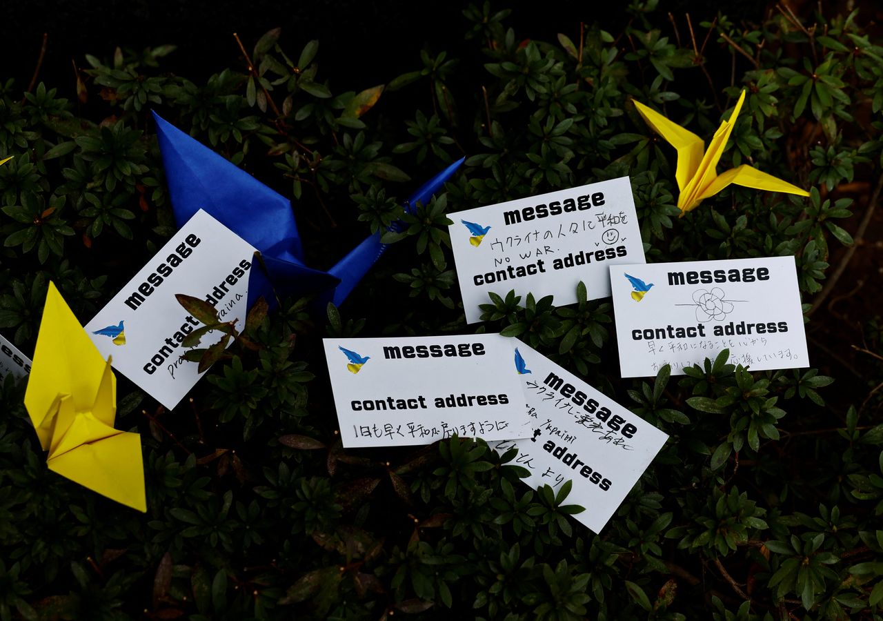 Messages to support Ukraine and paper cranes are placed in front of the Ukraine