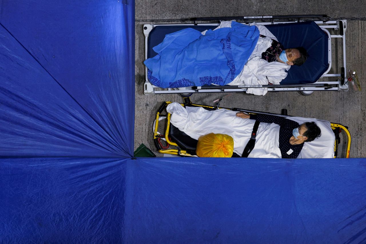 FILE PHOTO: Patients sleep at a makeshift coronavirus disease (COVID-19) treatment area, outside a hospital in Hong Kong, China March 1, 2022. REUTERS/Tyrone Siu