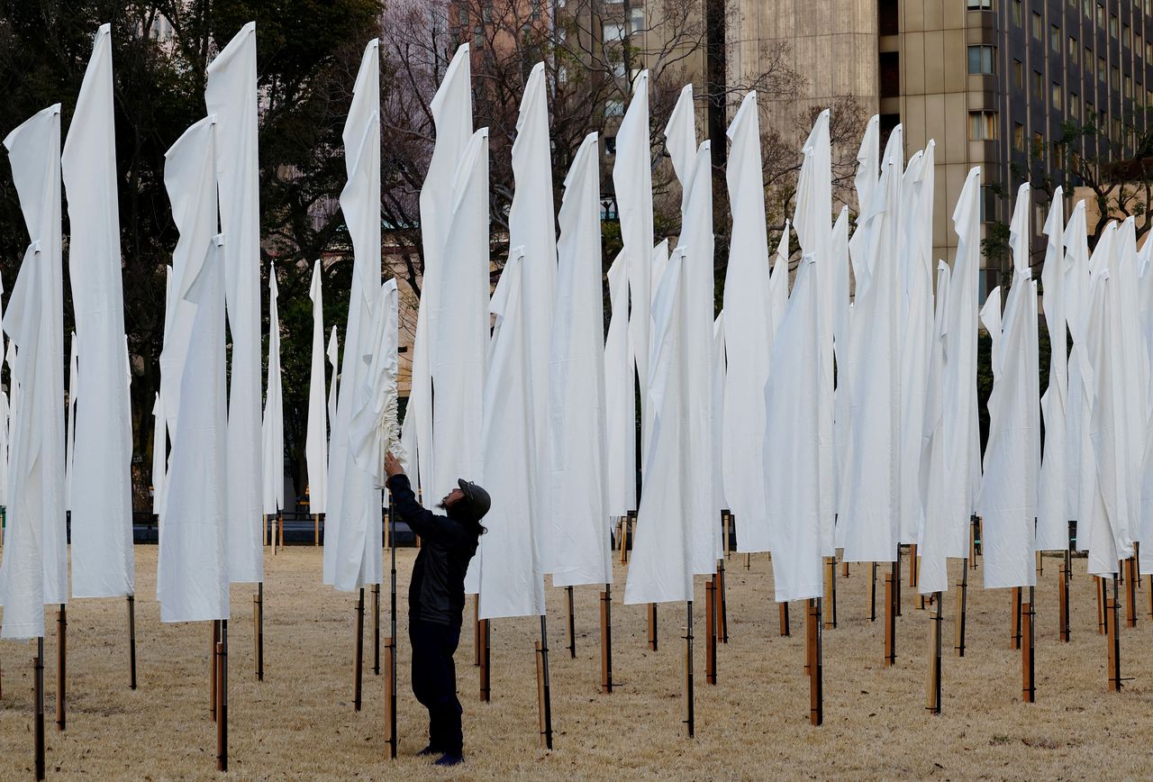 A man adjusts white flags at a park to mourn the victims of the March 11, 2011 earthquake and tsunami, one day before the 11th anniversary of the events that killed thousands and set off a nuclear crisis, in Tokyo, Japan March 10, 2022. REUTERS/Kim Kyung-Hoon