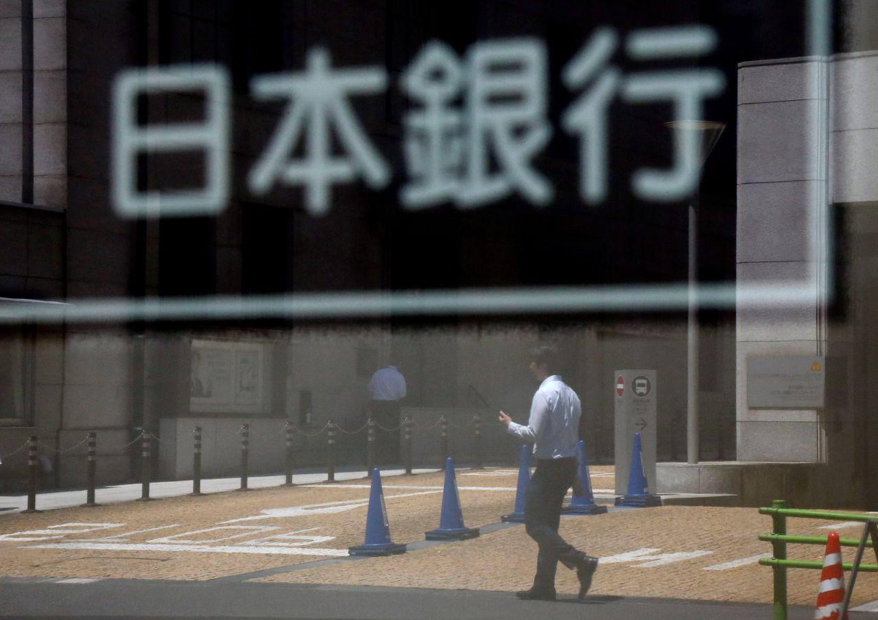 FILE PHOTO: A man is reflected in a sign board of the Bank of Japan building in Tokyo, Japan June 16, 2017. REUTERS/Toru Hanai