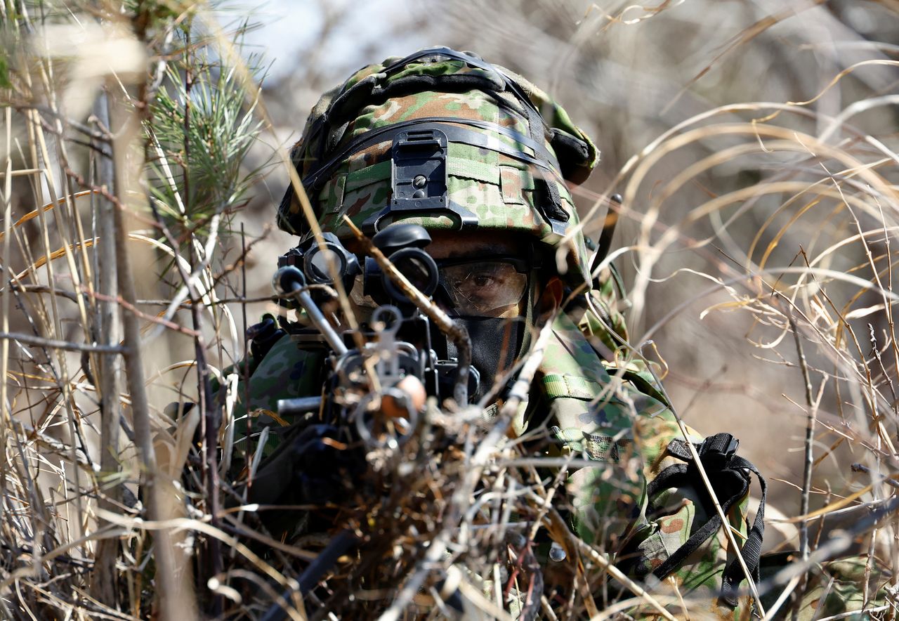 A member of the Japanese Self-Defense Force’s Amphibious Rapid Deployment Brigade aims his gun as he takes a position during joint airborne landing exercises with the U.S.Marine Corps near Mount Fuji at Higashifuji training field in Gotemba, west of Tokyo, Japan March 15,  2022. REUTERS/Kim Kyung-Hoon