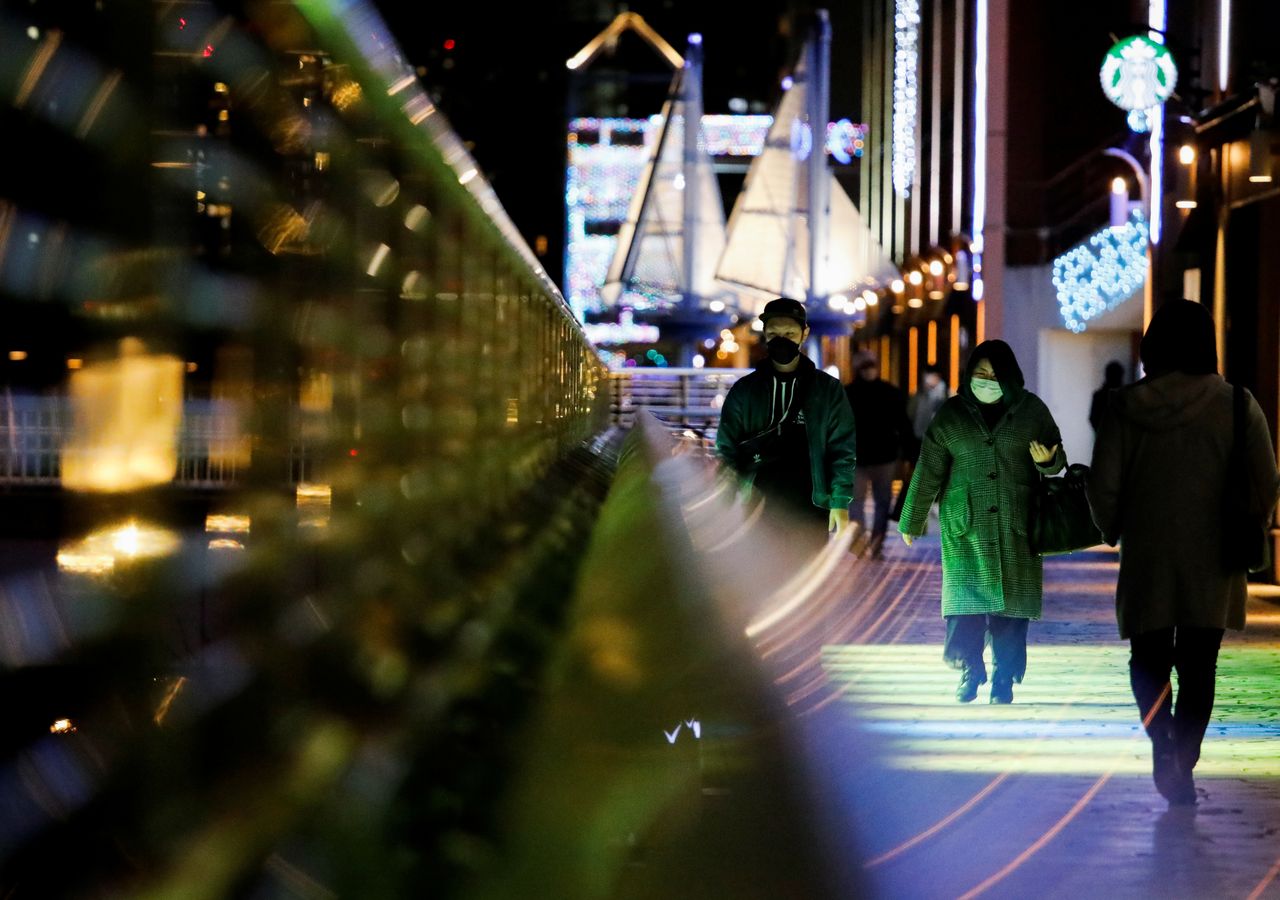 FILE PHOTO: Visitors wearing protective face masks walk on a pedestrian deck, amid the coronavirus disease (COVID-19) pandemic, in Tokyo, Japan January 22, 2022. REUTERS/Issei Kato