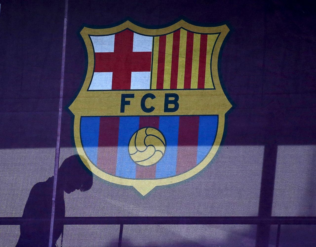 FILE PHOTO: A silhouette of a woman walks past behind a FC Barcelona