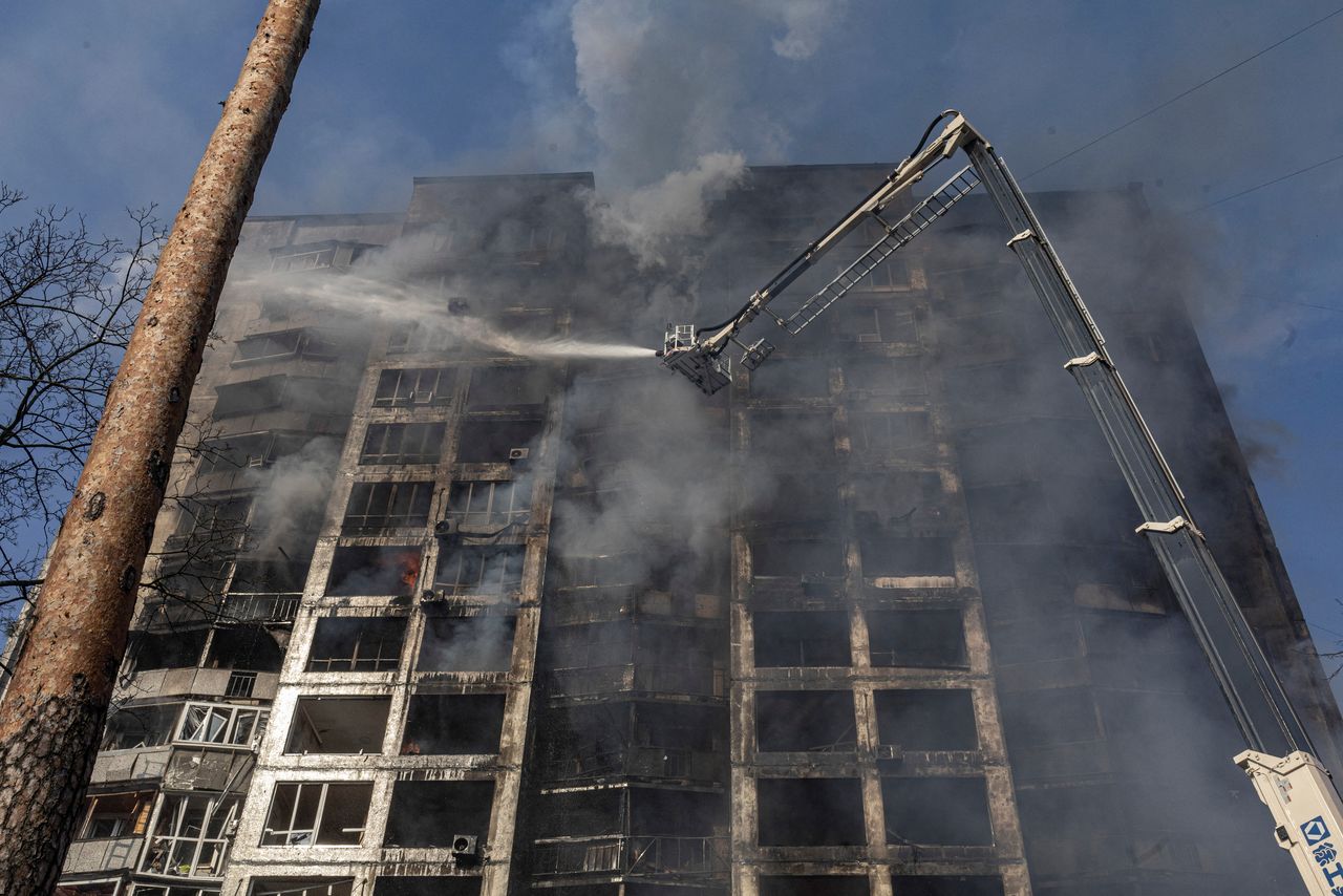 Firefighters work to put out a fire in a residential apartment building after it was hit by shelling as Russia