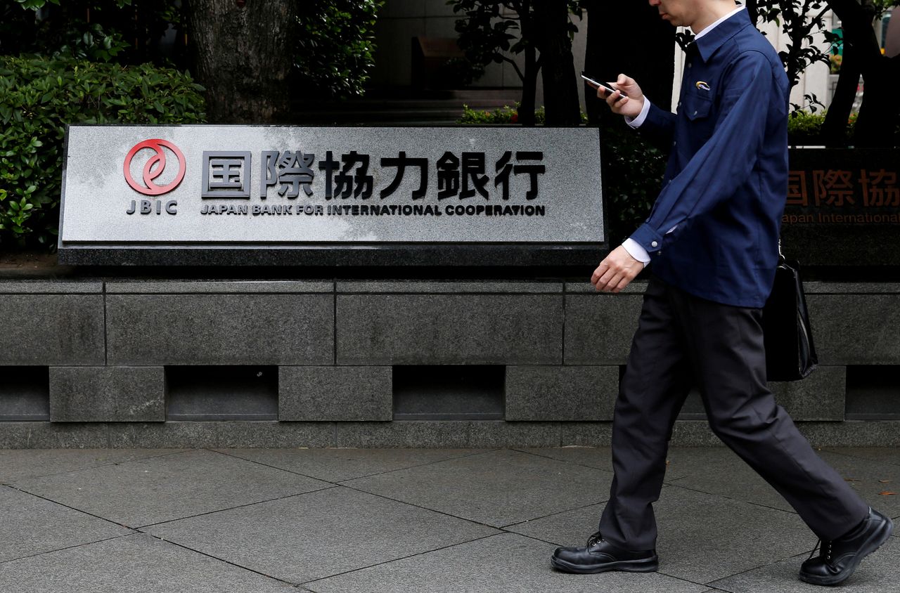 FILE PHOTO: A man walks past a sign of Japan Bank for International Cooperation (JBIC) at it