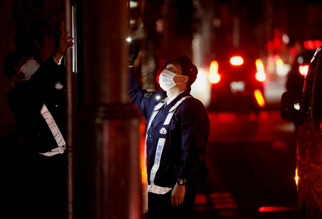 A police officer tries to restart traffic signals by attaching electric generator during an electric stoppage at the area after an earthquake in Tokyo, Japan March 17, 2022. REUTERS/Issei Kato