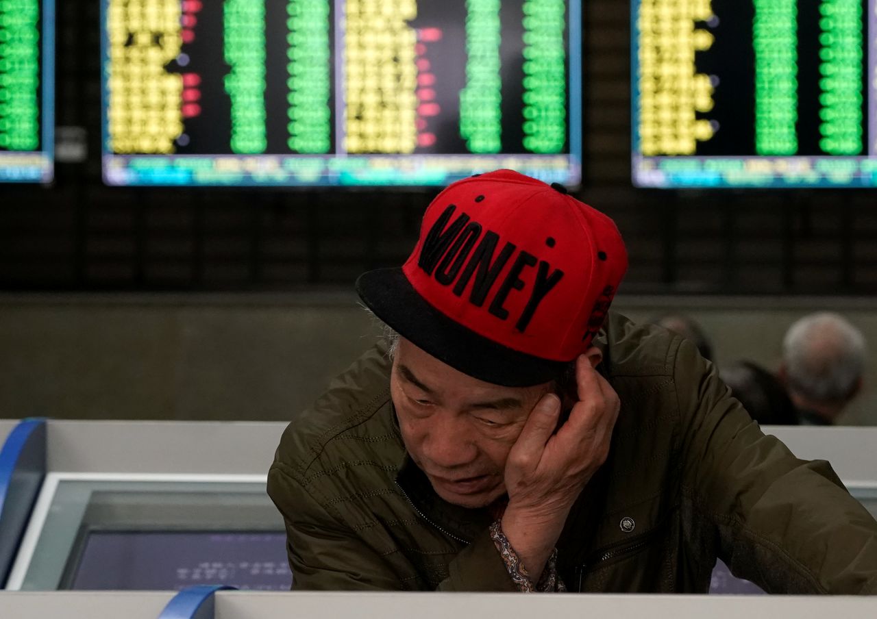 FILE PHOTO: An investor looks at computer screens showing stock information at a brokerage house in Shanghai, China May 6, 2019. REUTERS/Aly Song