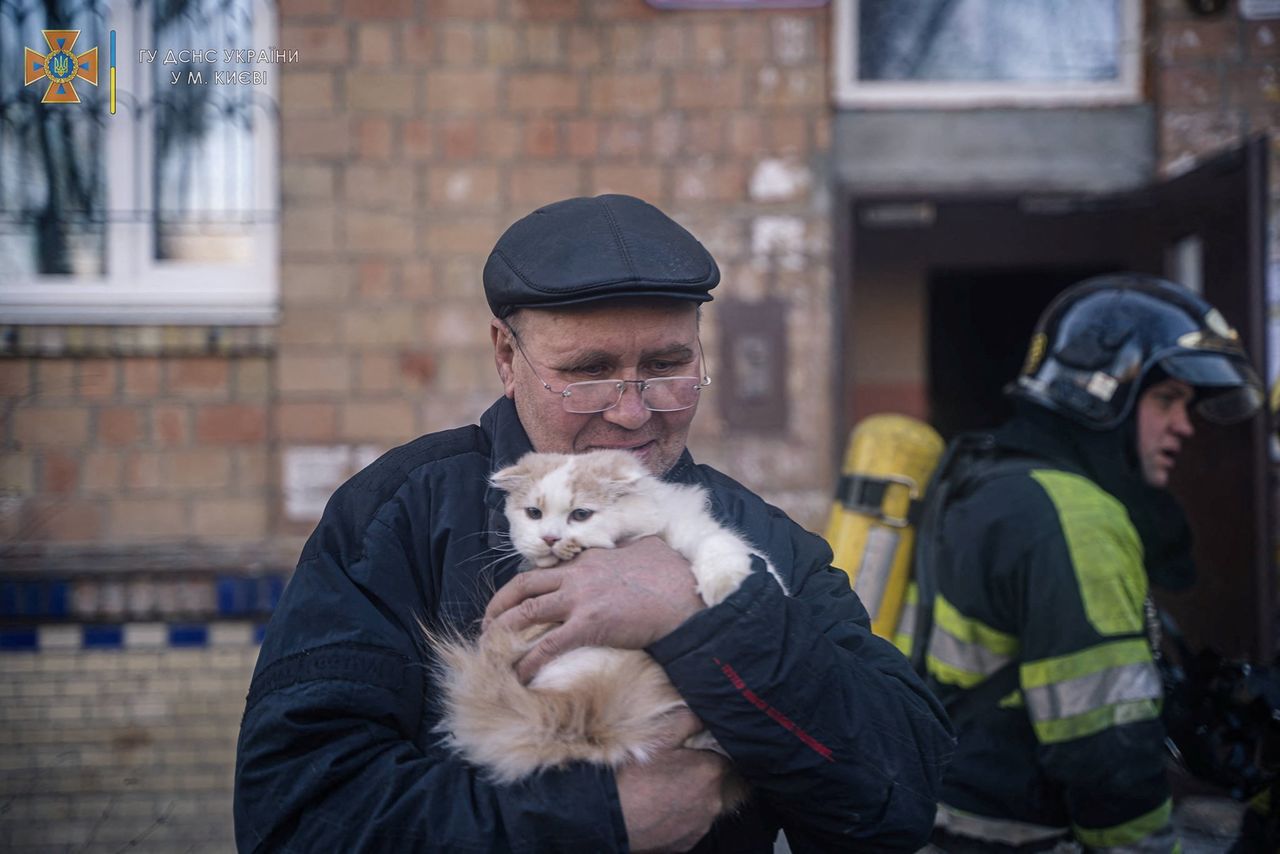 A man with a cat evacuates from a building damaged by shelling, as Russia