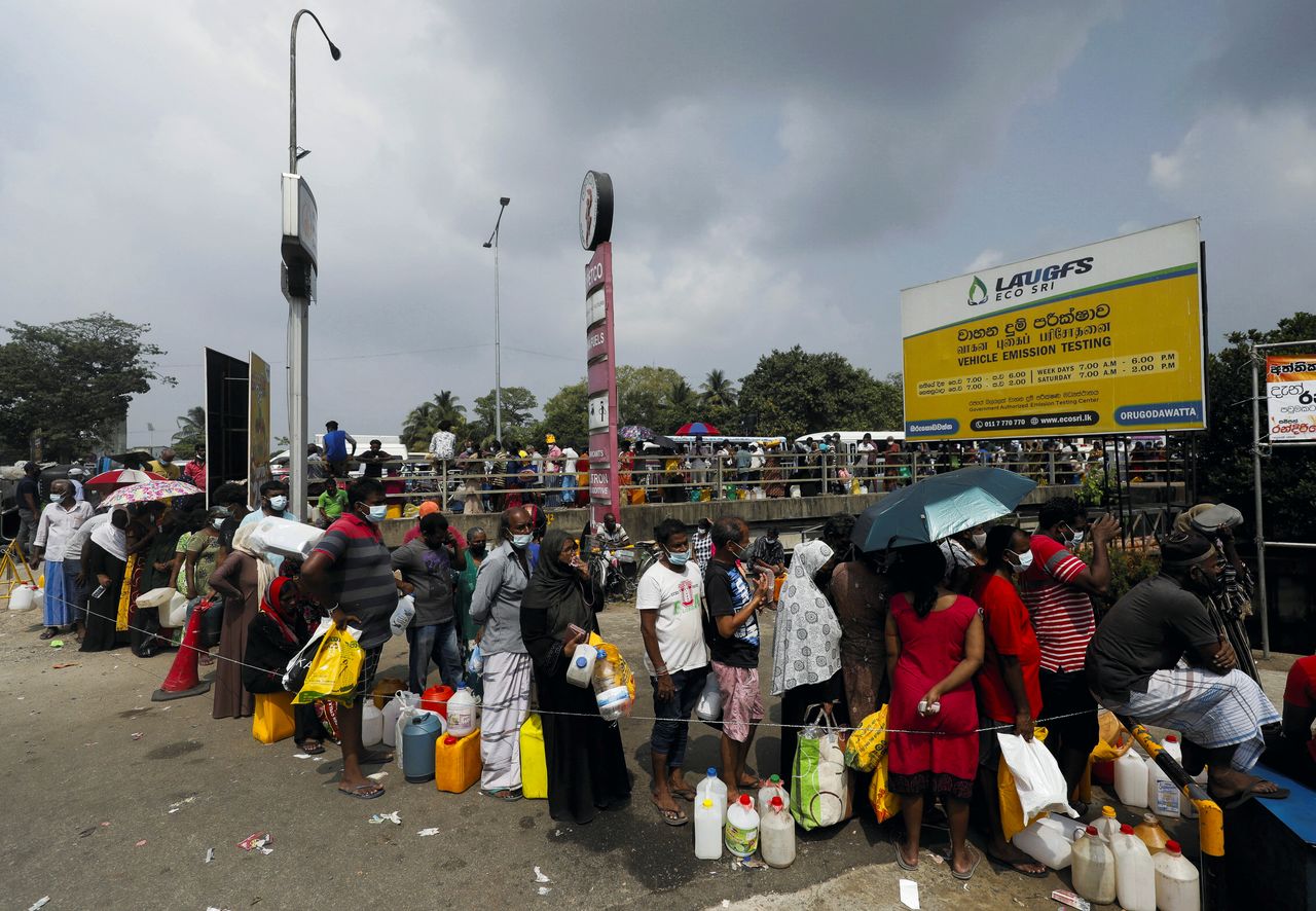 People stand in a long queue to buy kerosene oil due to shortage of domestic gas as a result of country