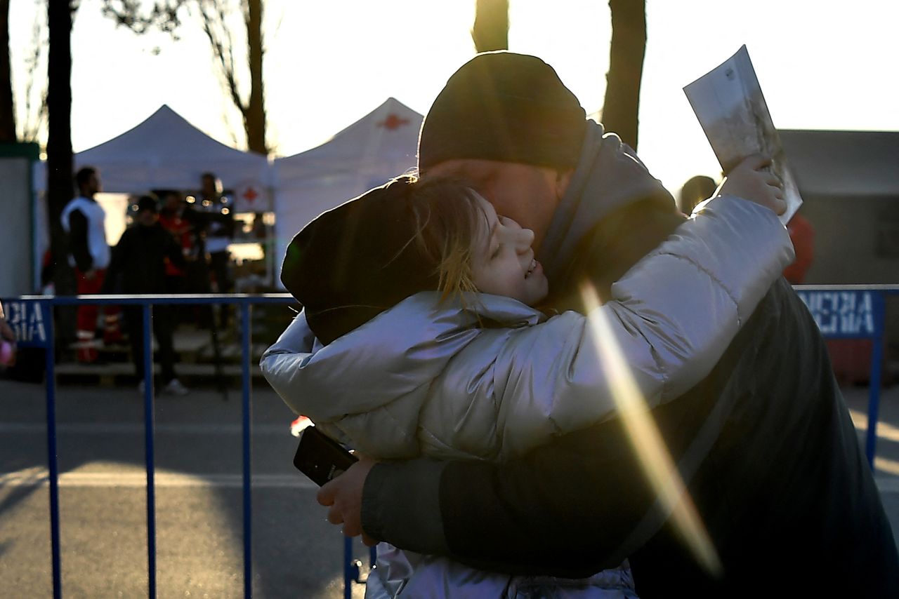 A girl embraces her father as he crossed the border after fleeing from Kharkiv in Ukraine to Romania, following Russia