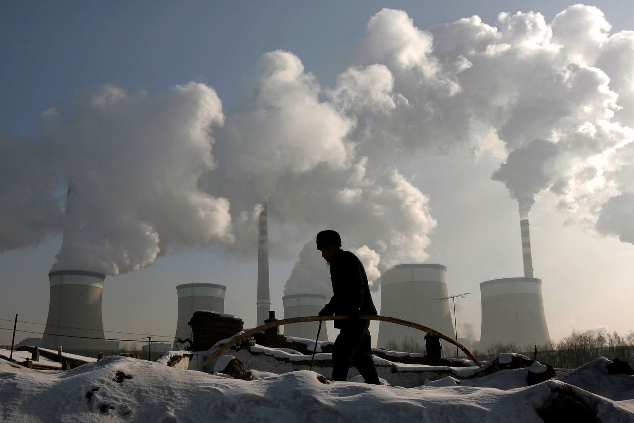 FILE PHOTO: A villager walks in front of a coal-fired power plant on the outskirts of Datong, Shanxi province, November 20, 2009. REUTERS/Jason Lee