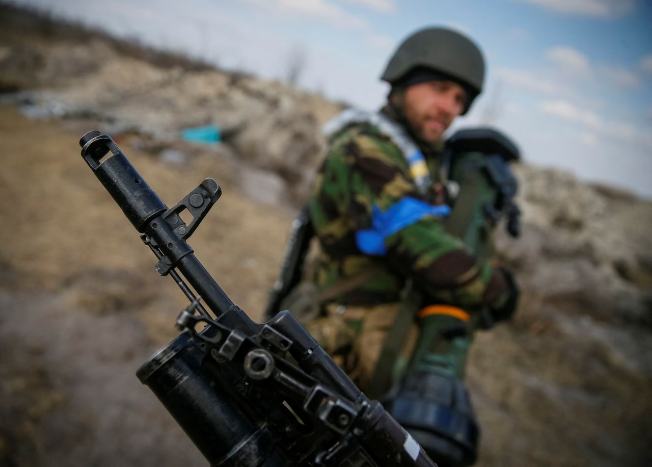 A Ukrainian service member holds a next generation light anti-tank weapon (NLAW) in front of another one holding a rifle at a position on the front line in the north Kyiv region, Ukraine March 24, 2022. REUTERS/Gleb Garanich