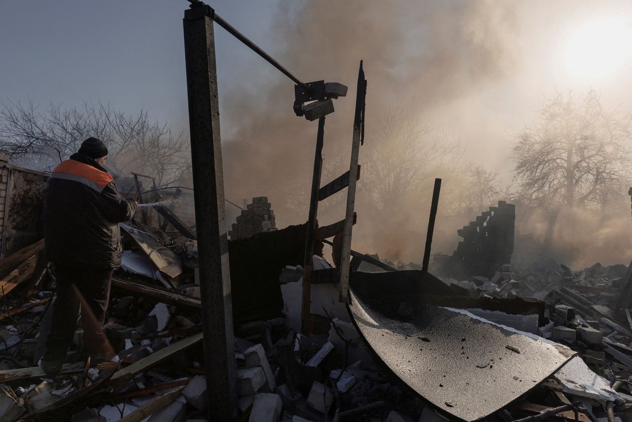 A resident extinguishes a fire after a bombing destroyed a family home in a northern district of Kharkiv as Russia