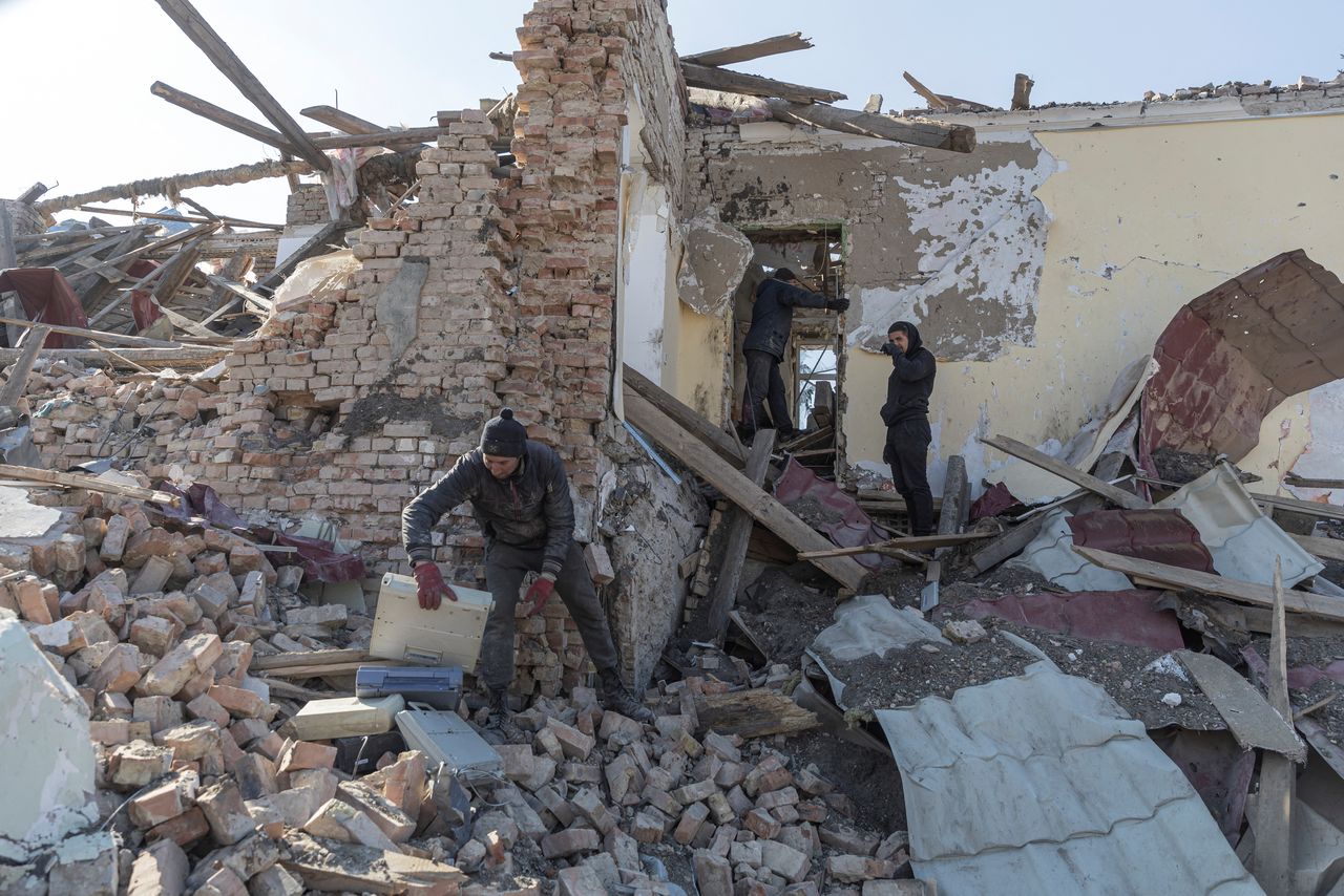 Locals clean up debris from the cultural centre destroyed in shelling earlier this month, as Russia