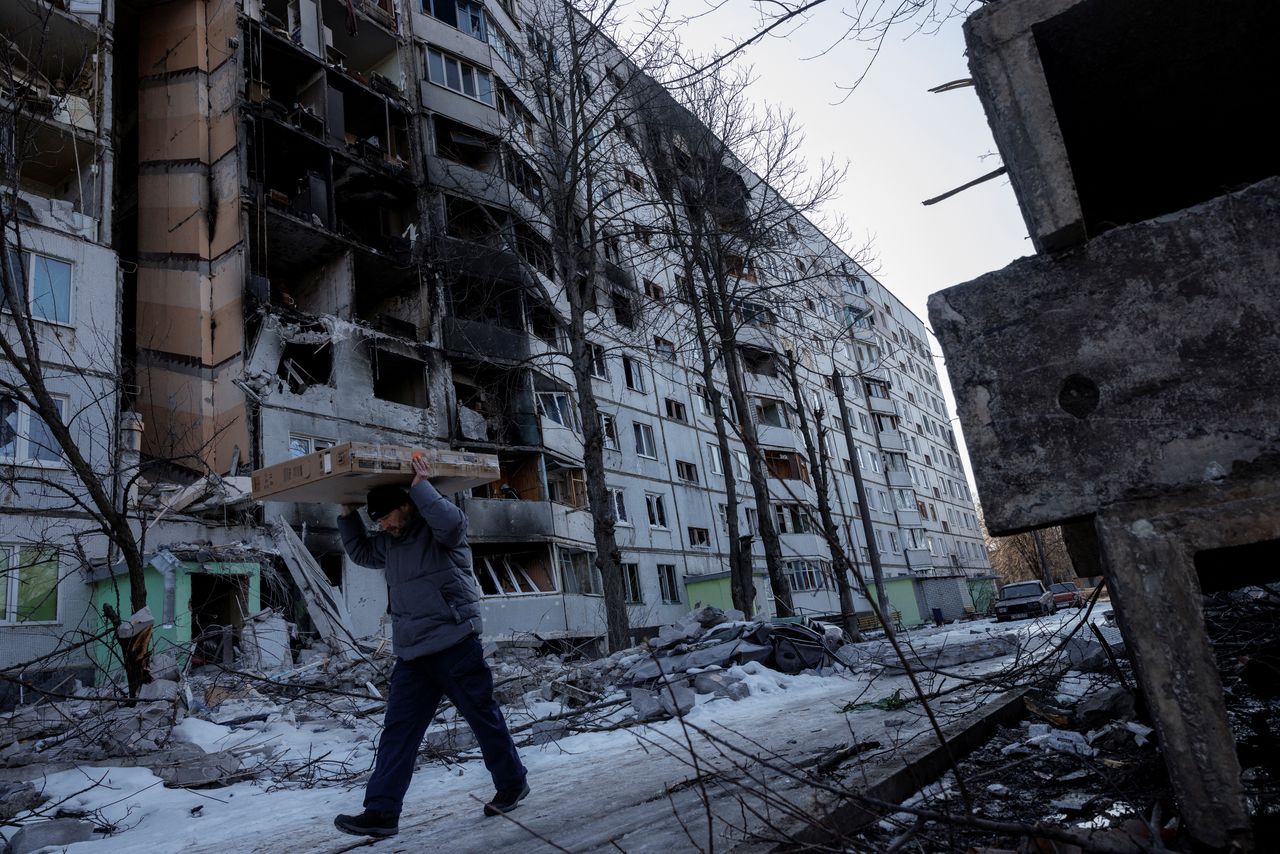 A man carries belonging out of a house that was hit by bombing in a northern district of Kharkiv as Russia