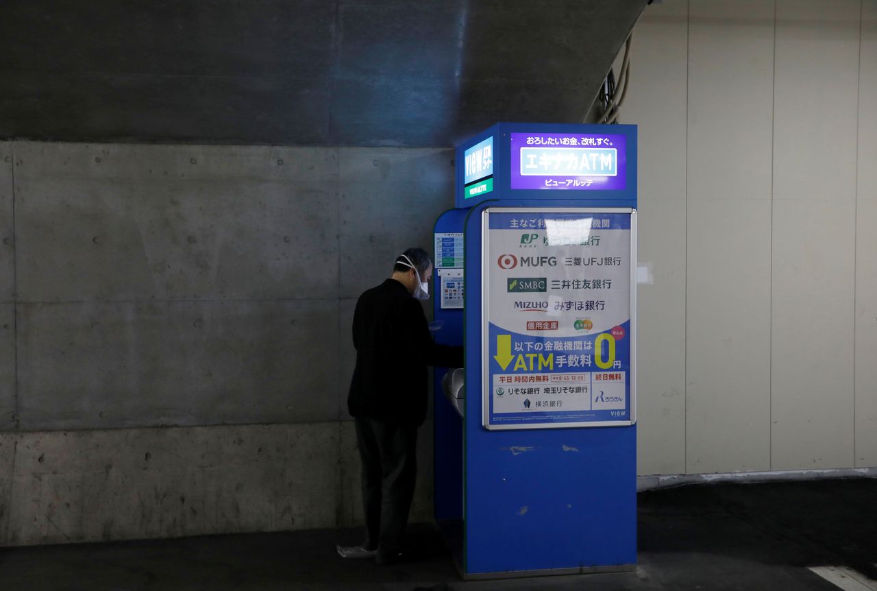 A man wearing a protective mask, amid the coronavirus disease (COVID-19) outbreak, uses the ATM machine at a subway station in Tokyo, Japan, January 8, 2021. REUTERS/Kim Kyung-Hoon/File Photo