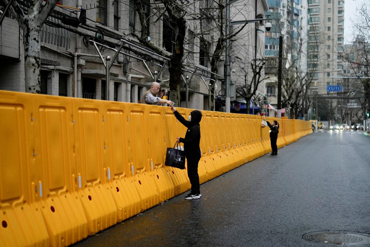 FILE PHOTO: People pass food to residents over the barriers of an area under lockdown, amid the coronavirus disease (COVID-19) pandemic, in Shanghai, China March 25, 2022. REUTERS/Aly Song/File Photo