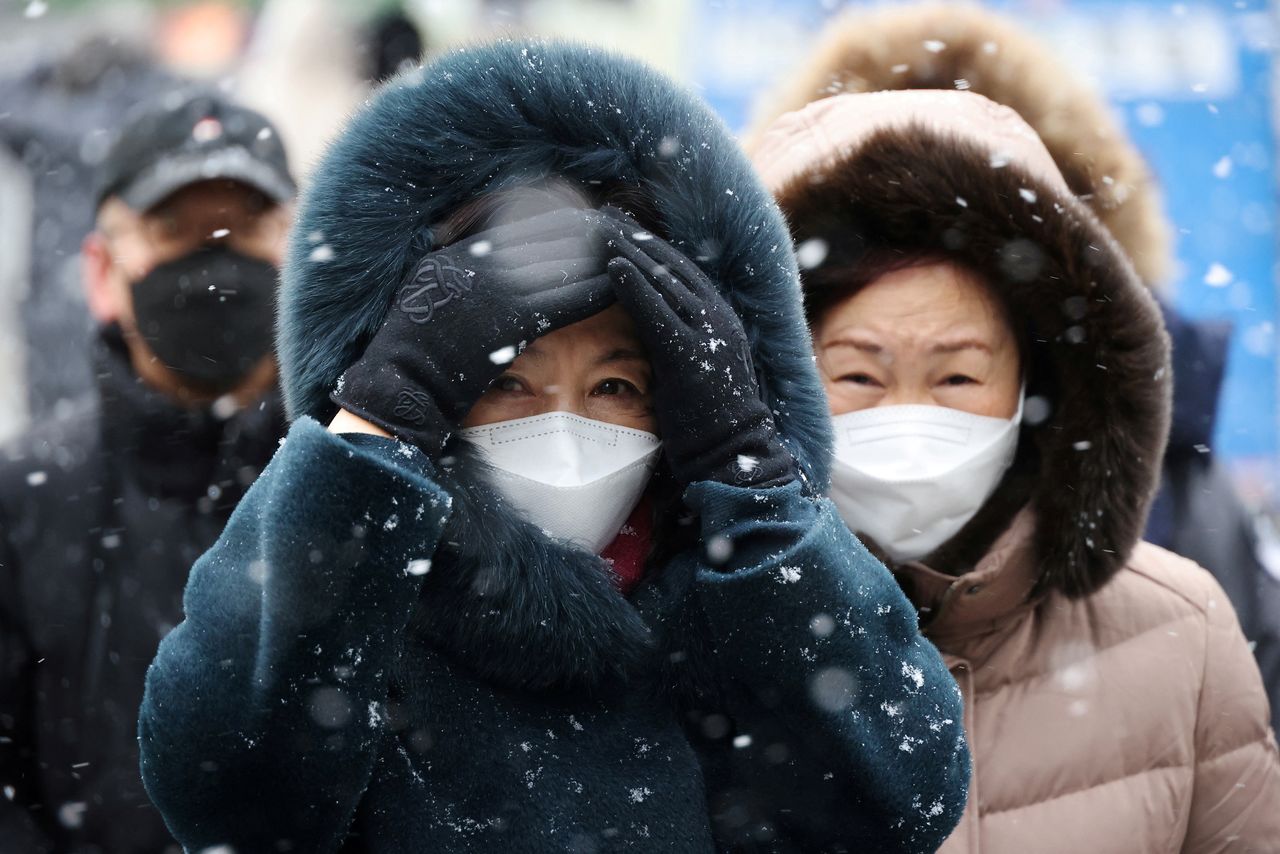 FILE PHOTO: Commuters walk during snowfall, amid the coronavirus disease (COVID-19) pandemic, in central Seoul, South Korea, January 17, 2022.    REUTERS/Kim Hong-Ji/File Photo