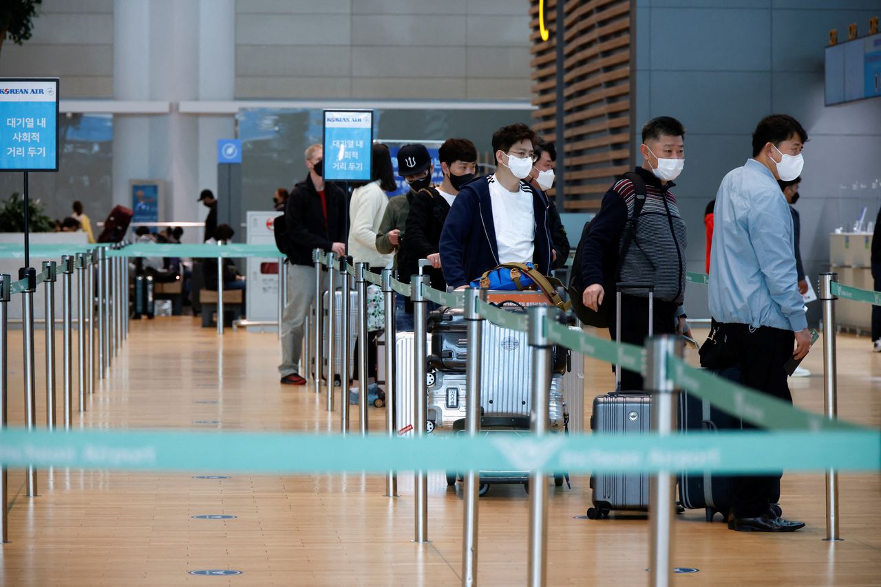 People wearing face masks to prevent from contracting the coronavirus disease (COVID-19) wait in line to check in at Incheon International Airport, in Incheon, South Korea, March 25, 2022. Picture taken March 25, 2022. REUTERS/Heo Ran