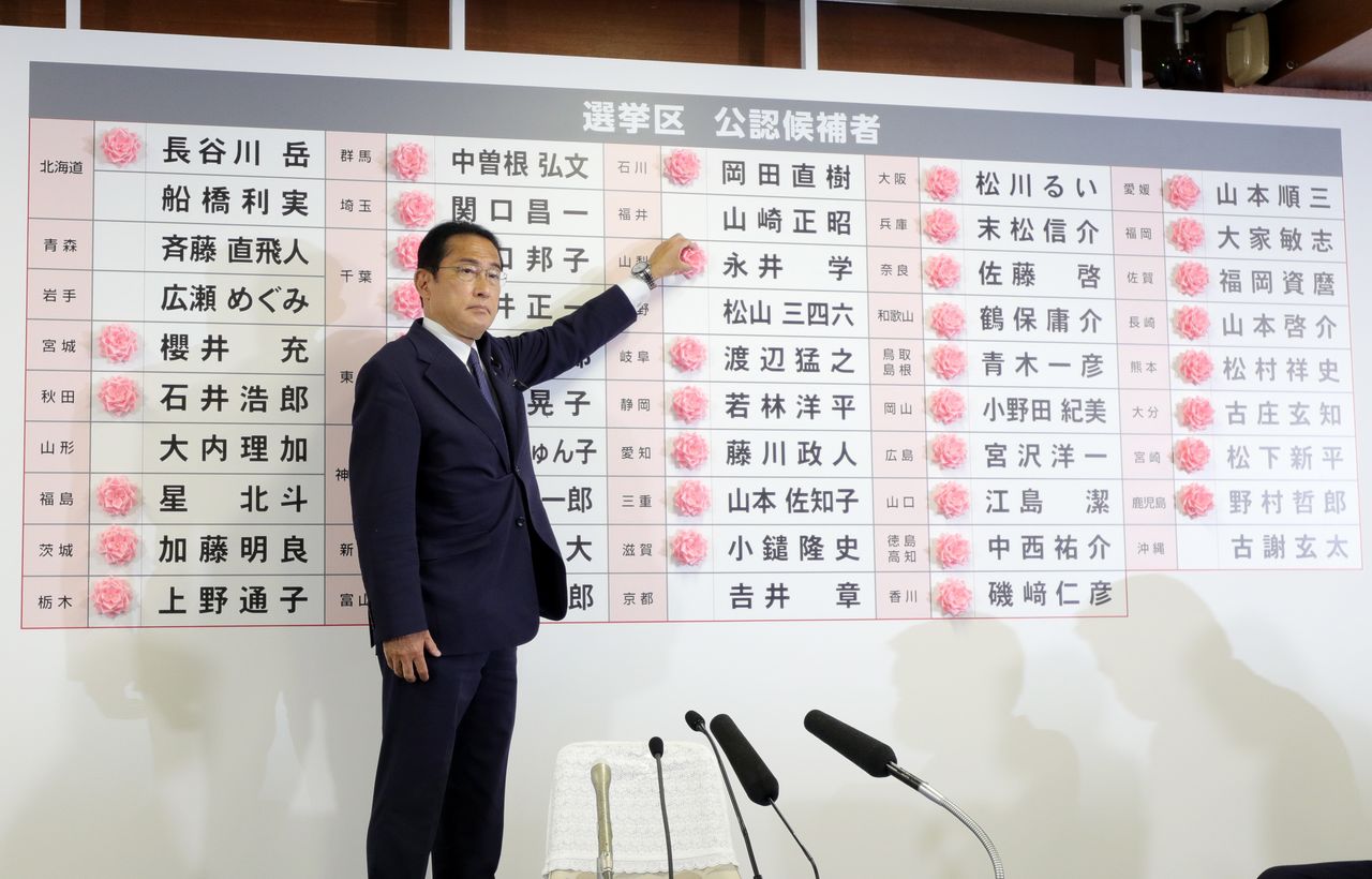 Prime Minister Kishida Fumio places flowers next to the names of winning candidates at LDP headquarters in Tokyo on July 10, 2022. (© Jiji)