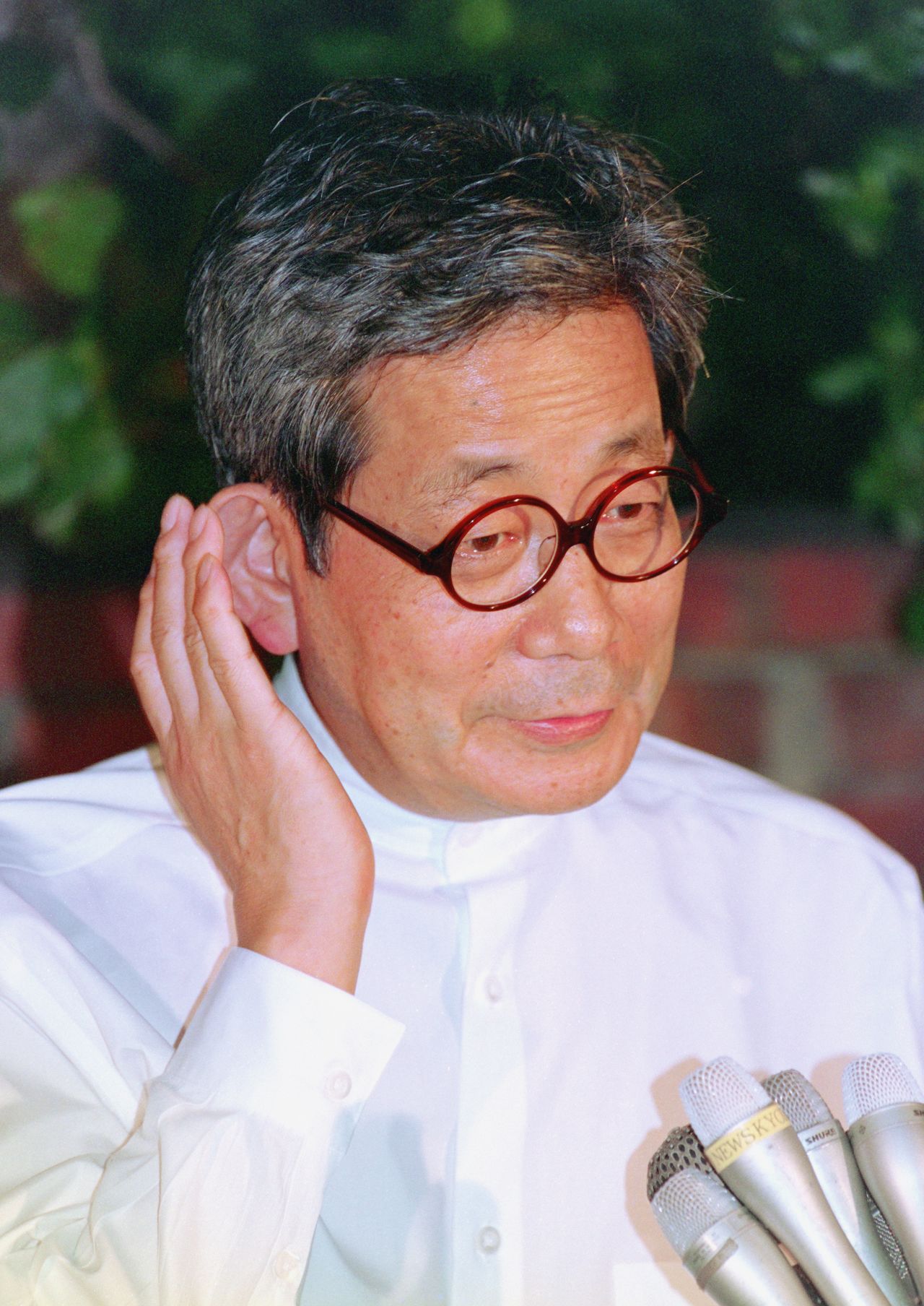 Ōe Kenzaburō speaks to reporters outside his house after winning the Nobel Prize in Literature on October 13, 1994. (© Jiji)