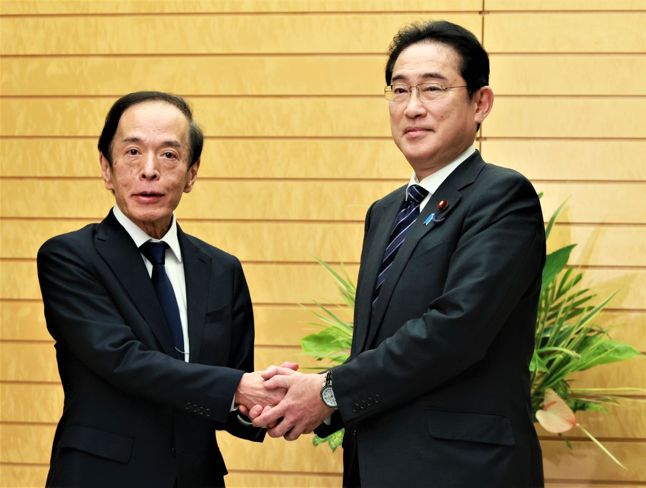 Ueda Kazuo (left) shakes hands with Prime Minister Kishida Fumio after he is appointed as governor of the Bank of Japan. (© Jiji)