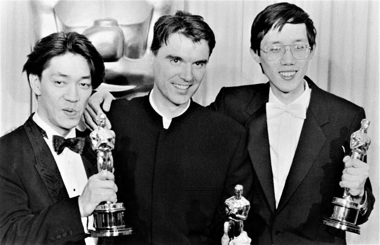 From left: Sakamoto Ryūichi, David Byrne, and Cong Su with their Academy Awards for Best Original Score for The Last Emperor in Hollywood on April 12, 1988. (© AFP/Jiji)