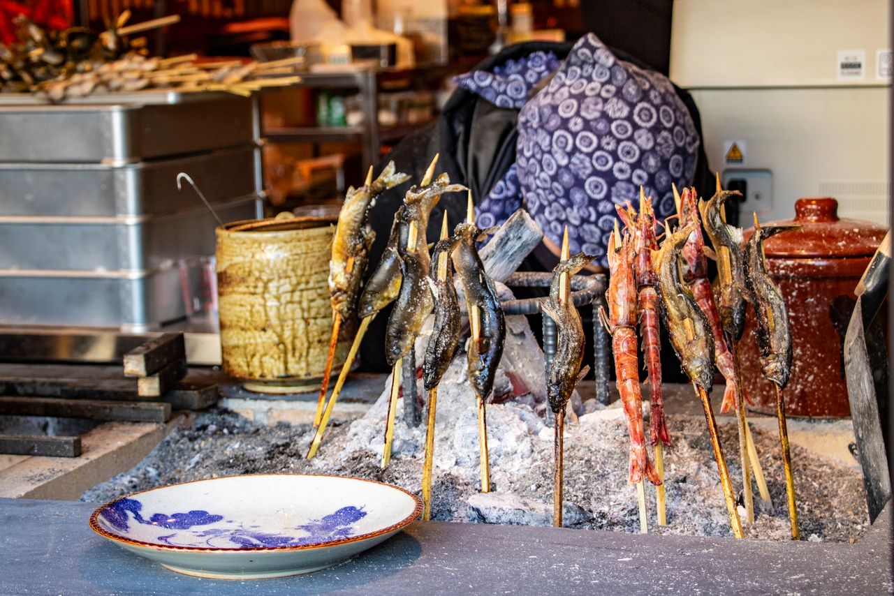 Fresh fish grill around burning charcoals in the traditional robatayaki style of cooking. (© Nippon.com)
