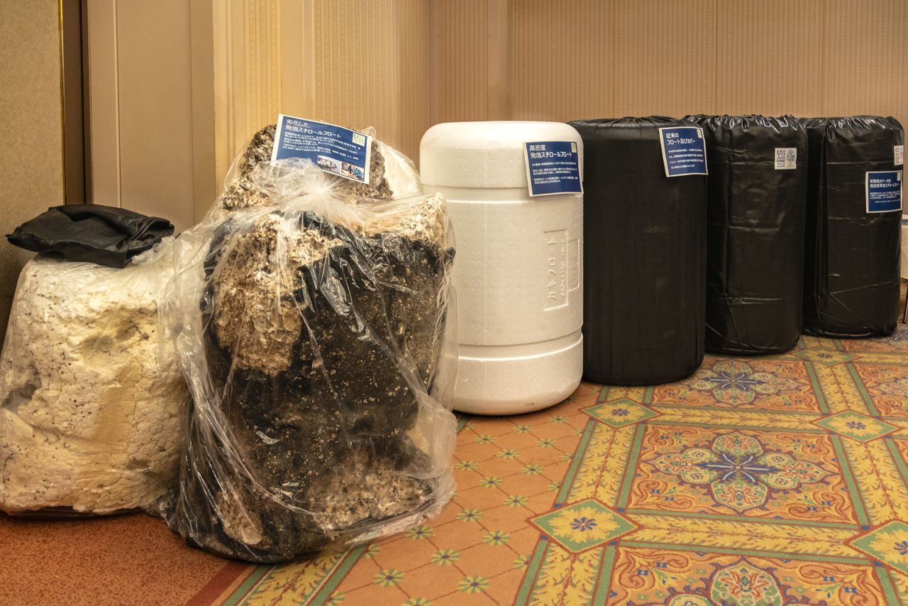 The two floats on the right are newly developed high-density models with protective black covers. The white one in the center is the float body that goes inside the cover. Between these is the standard model. In the front left is a discarded float found on the shore. (© Nippon.com)