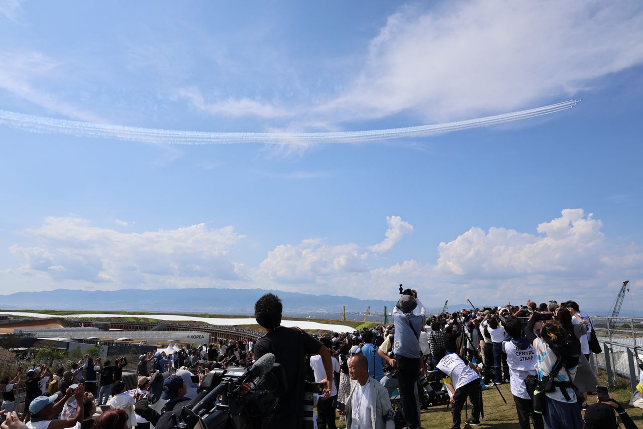 Spectators watch Blue Impulse aircraft perform in the skies over the Expo 2025 Osaka Kansai venue on July 12, 2025. (© Jiji)