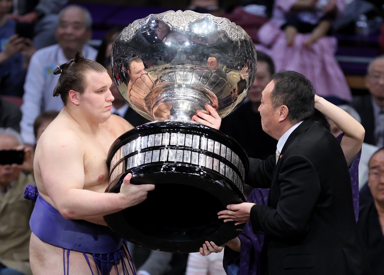 Aonishiki receives the Prime Minister’s Cup from Inoue Takahiro, an advisor to Prime Minister Takaichi. (© Jiji)
