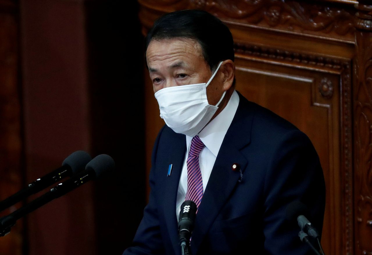FILE PHOTO: Japan's Deputy Prime Minister and Finance Minister Taro Aso, wearing a protective face mask, delivers his policy speech at the opening of an ordinary session of the parliament in Tokyo, Japan January 18, 2021. REUTERS/Issei Kato