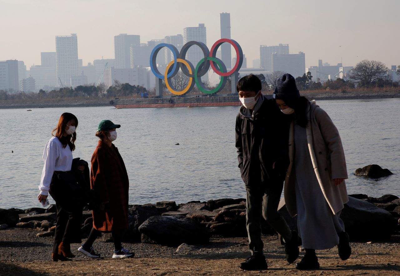 FILE PHOTO: People wearing protective masks, amid the coronavirus disease (COVID-19) outbreak, are seen in front of the giant Olympic rings in Tokyo, Japan, January 22, 2021. REUTERS/Kim Kyung-Hoon