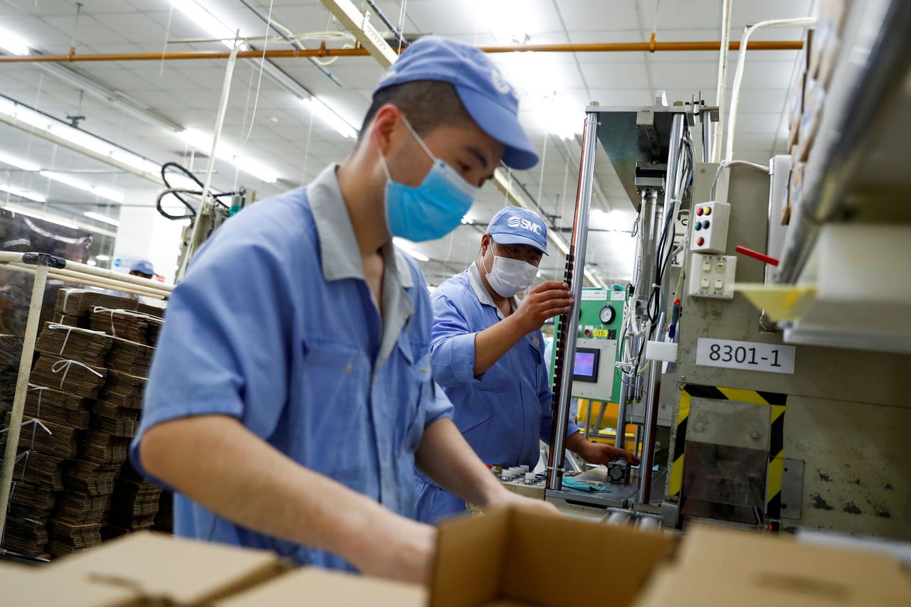 FILE PHOTO: Employees wearing masks work at a factory of the component maker SMC during a government organised tour of its facility following the outbreak of the coronavirus disease (COVID-19), in Beijing, China May 13, 2020. REUTERS/Thomas Peter/File Photo/File Photo