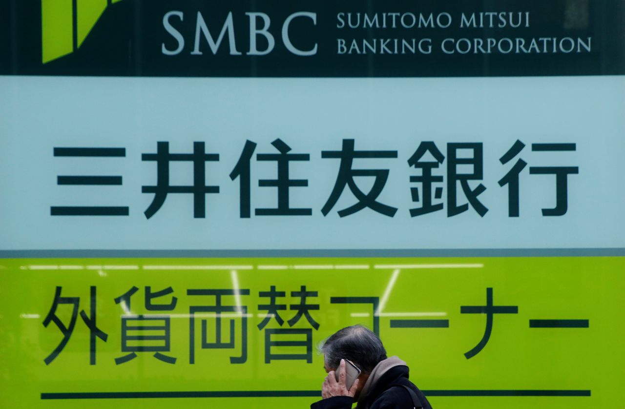 FILE PHOTO: A man walks past a sign board of Sumitomo Mitsui Banking Corporation, part of Sumitomo Mitsui Financial Group Inc (SMFG) outside its branch in Tokyo, Japan, January 27, 2017. REUTERS/Toru Hanai