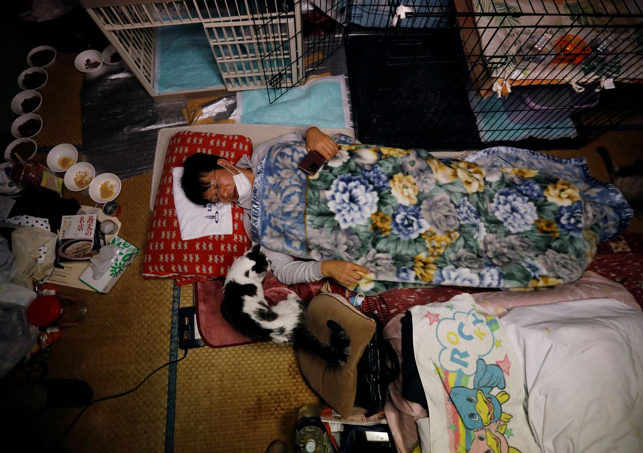 Sakae Kato lies in bed next to Charm, a cat who he rescued five years ago who is infected with feline leukemia virus, at his home in a restricted zone in Namie, Fukushima Prefecture, Japan, February 20, 2021. Kato looks after 41 cats in his home and another empty building on his property. A decade ago, he stayed behind to rescue cats abandoned by neighbours who fled the radiation clouds belching from the nearby Fukushima nuclear plant. He won't leave. I want to make sure I am here to take care of the last one,
